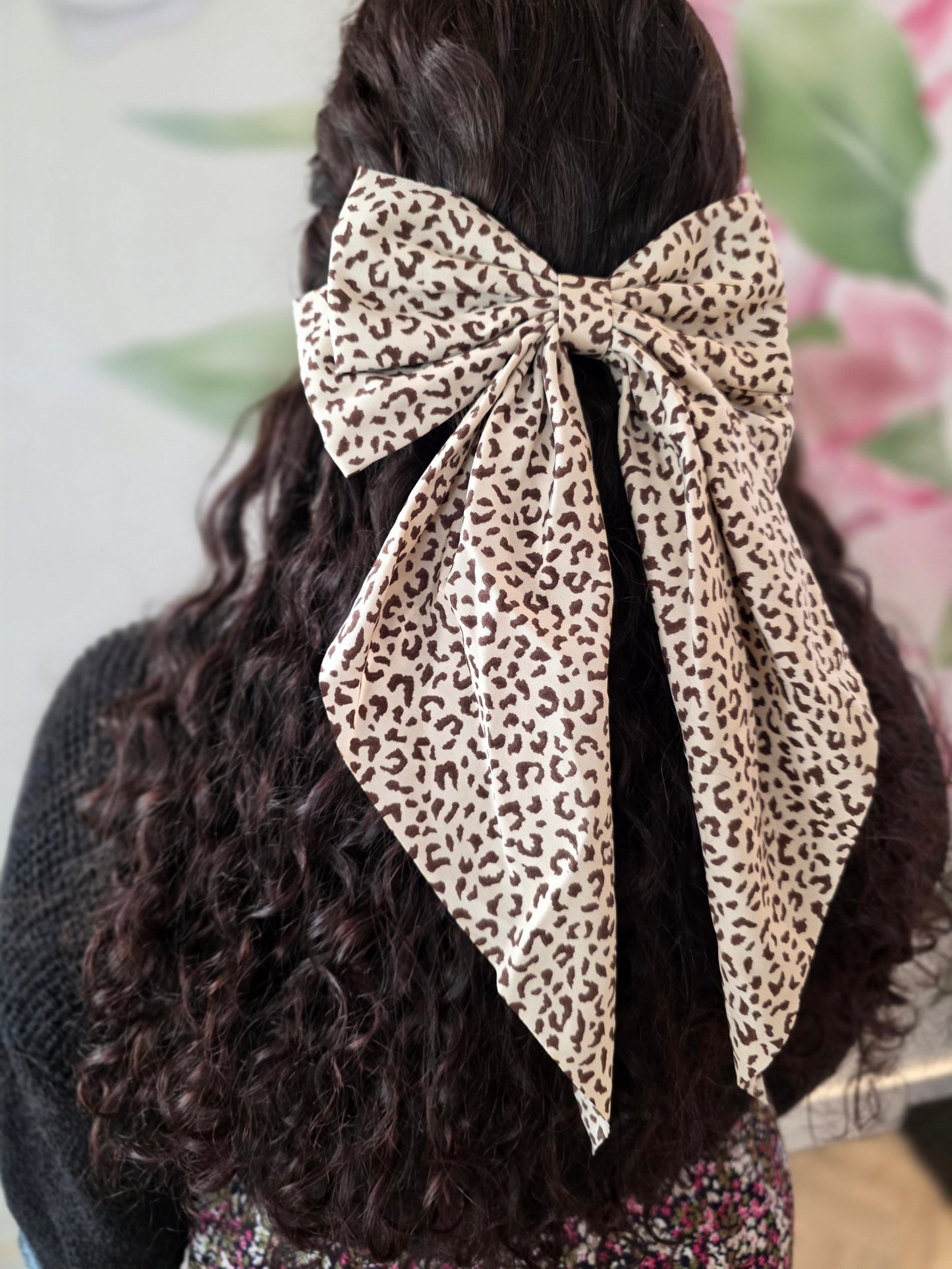 Leopard print hair bow on a person's head with a blurred background