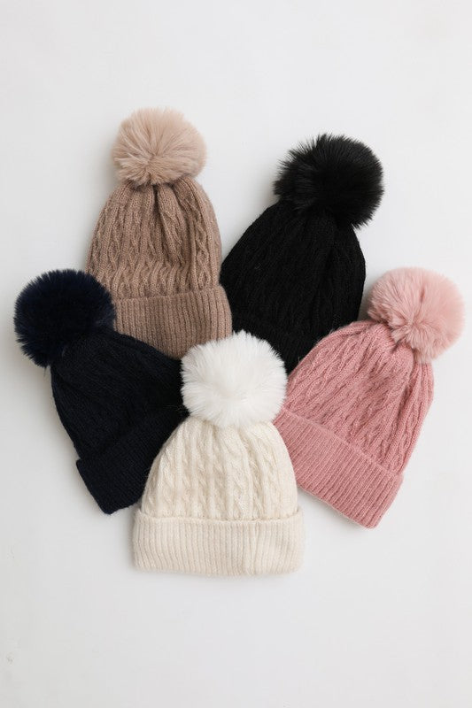 Five knit hats with pom-poms in various colors on a light background