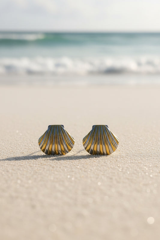 Pair of shell-shaped earrings in gold and silver on a textured beige background