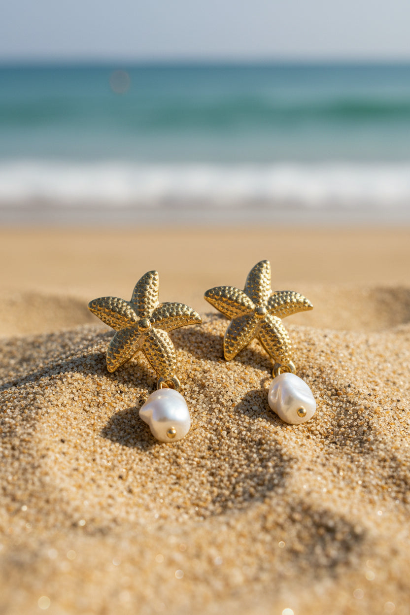Gold starfish earrings with pearls on a textured surface