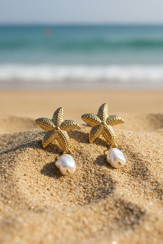 Gold starfish earrings with pearls on a textured surface
