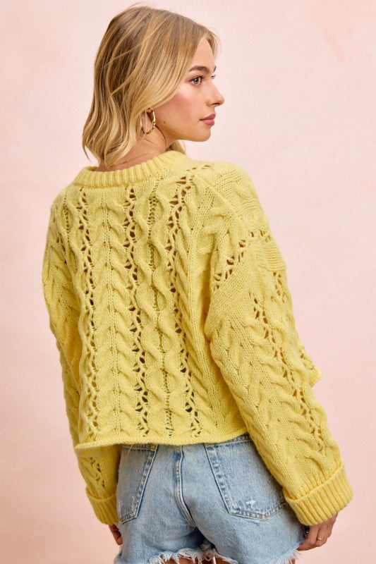 Woman wearing a yellow knitted sweater against a pink background