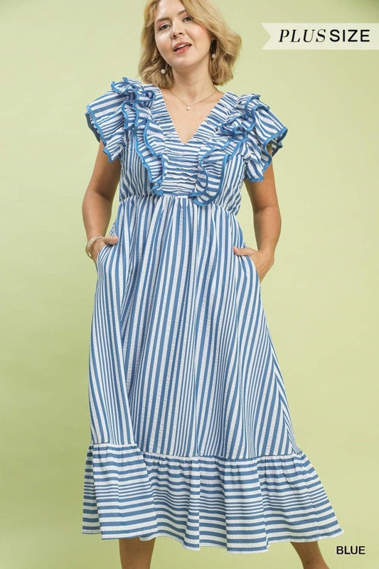 Woman wearing a blue and white striped dress with ruffled details on a light green background.