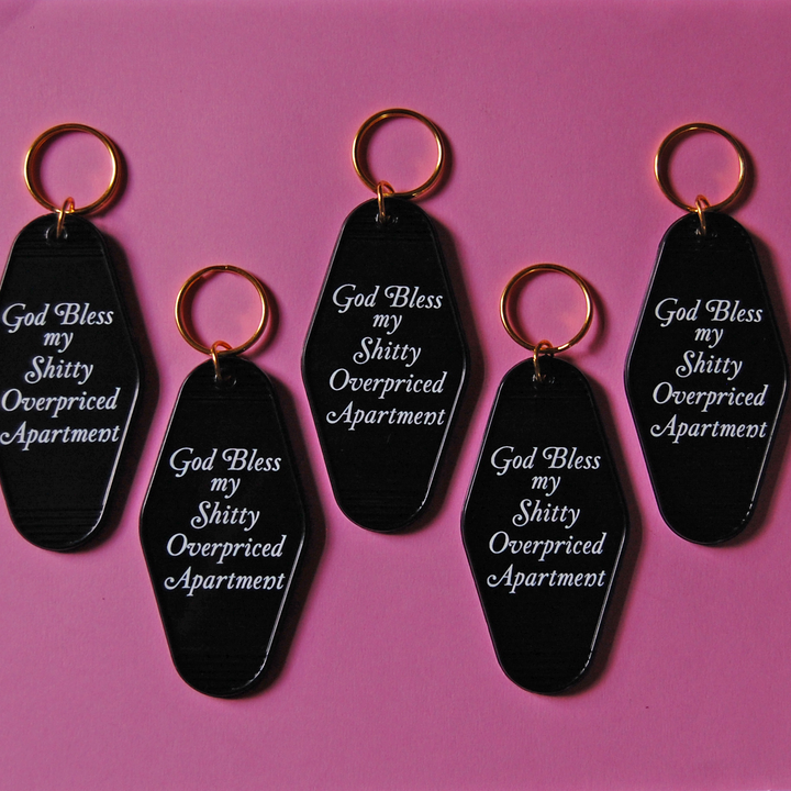 "God Bless my Shitty, Overpriced Apartment" Motel Keychain (Black)